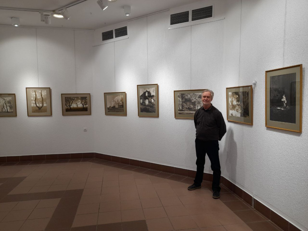 Виктор Сутягин на фоне персональной выставки. 2025 г.